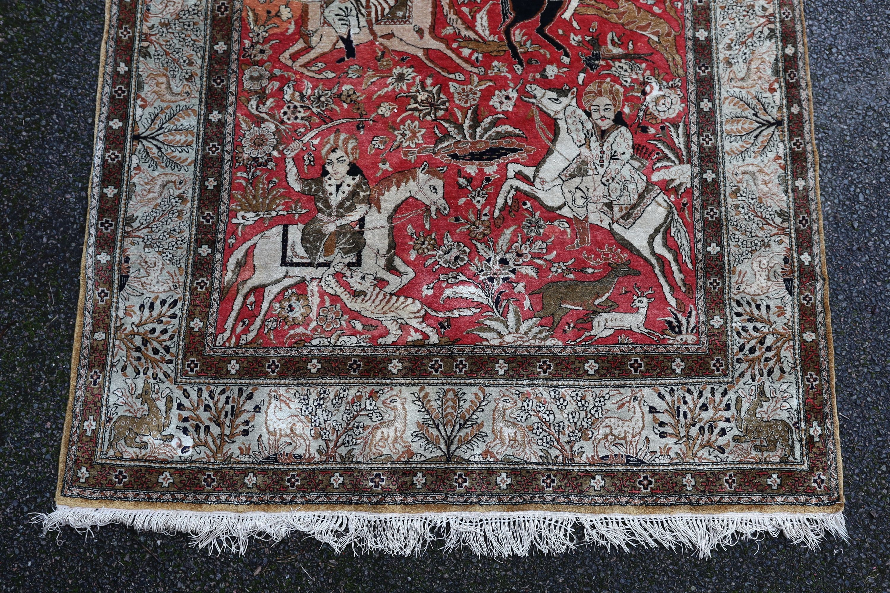 An early 20th century Tabriz pictorial red ground rug, woven with hunters on horseback, 208 x 135cm.